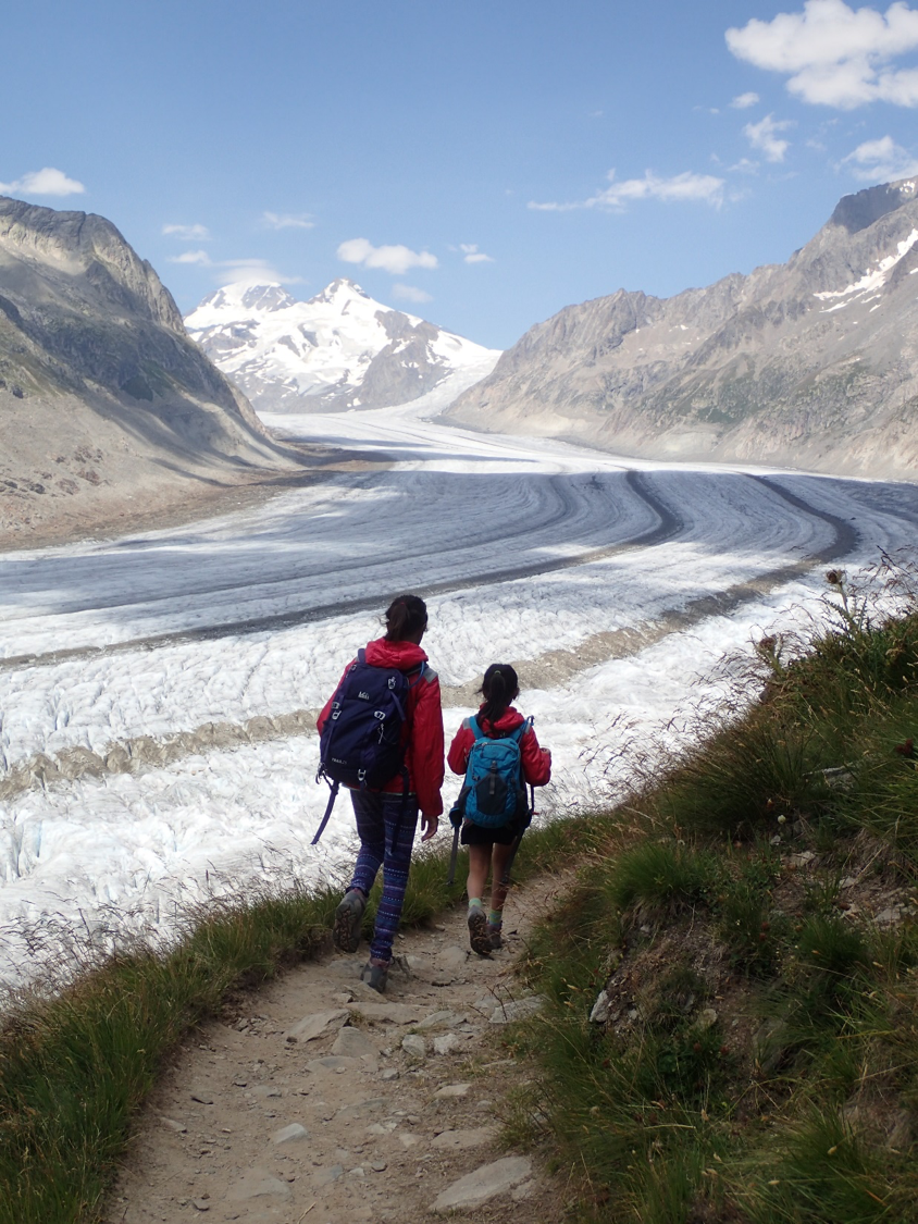 Two children walk along a path towards icy mountains