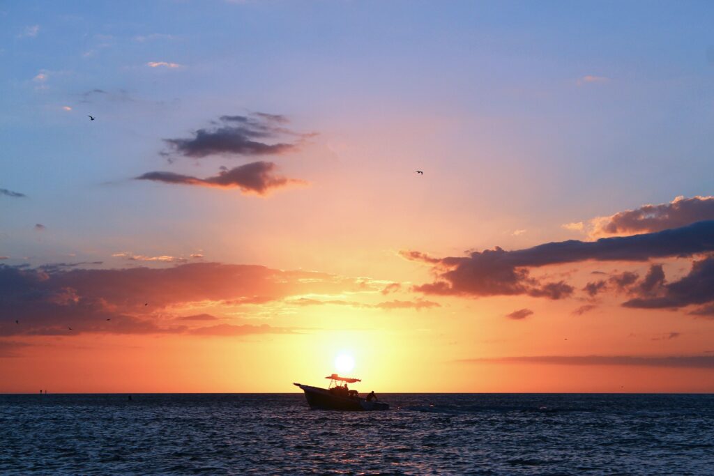 A scenic view of a boat in front of a pink sunset