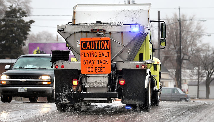 A salt truck with a caution sign on the back