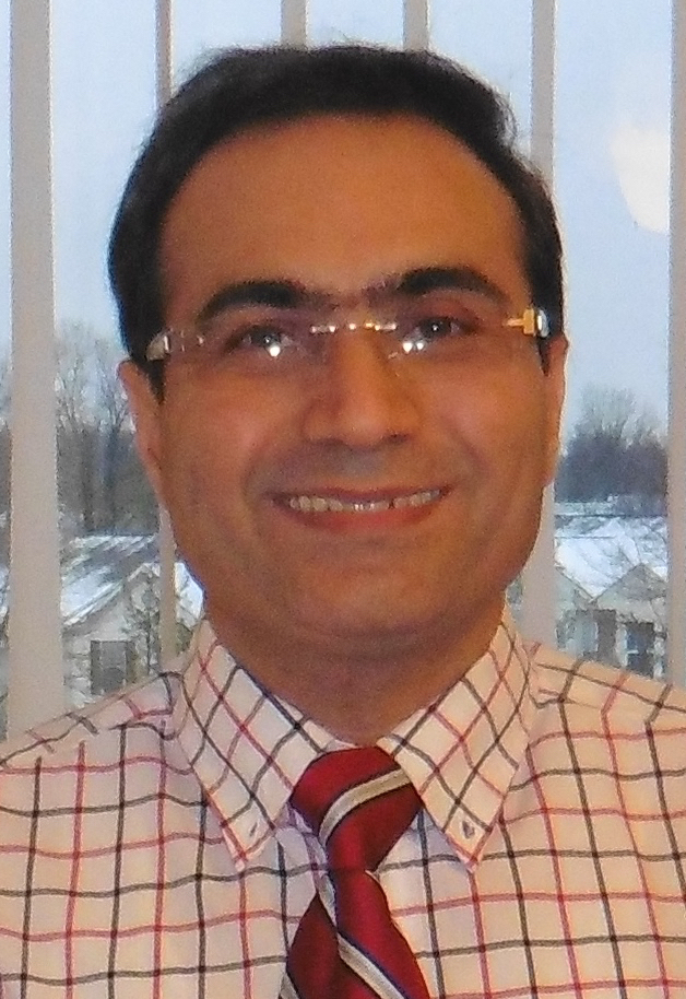 Isaac Moradi smiles for the camera, wearing a red gridded button-up and a red tie