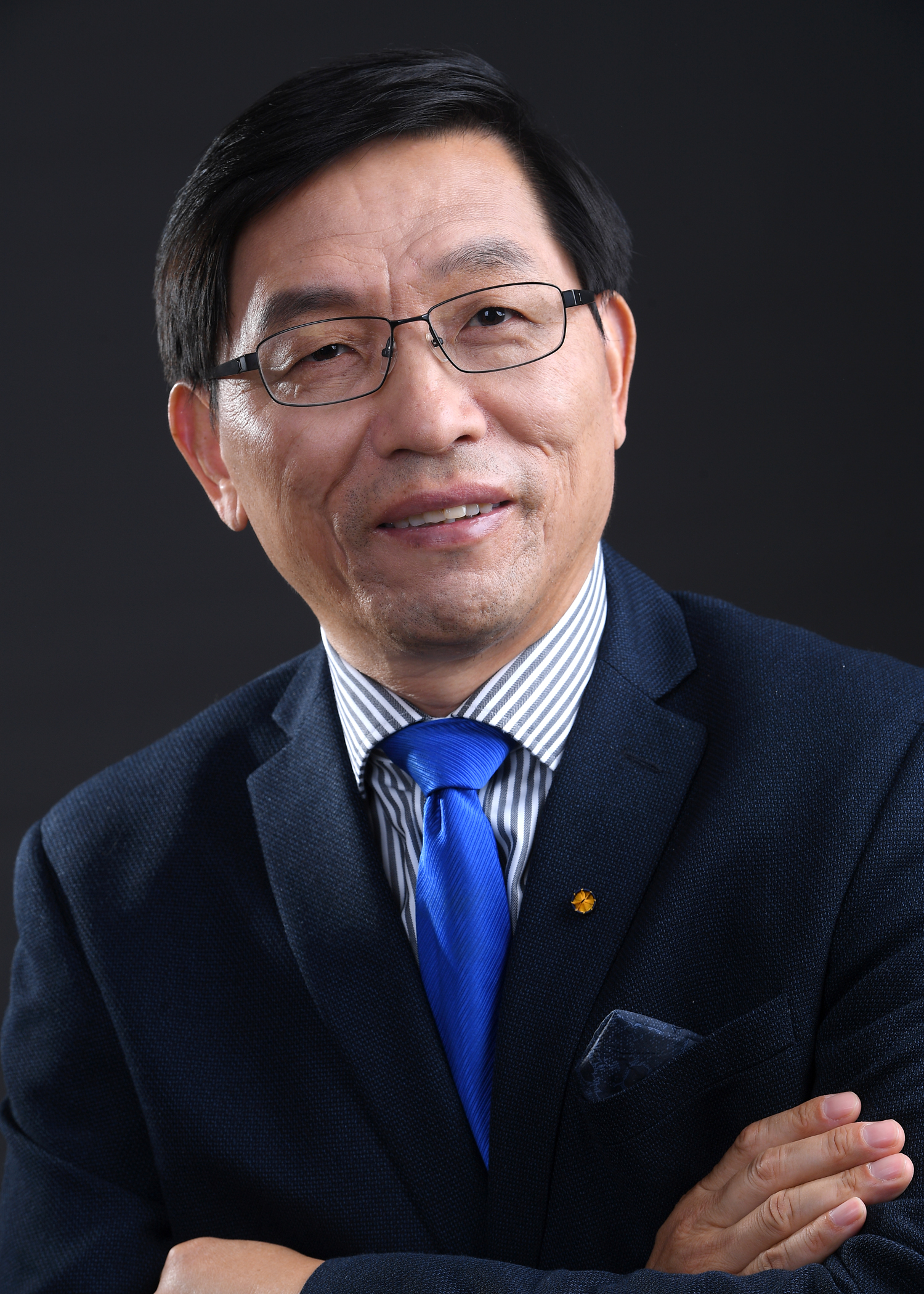 Dr. Zhanqing Li crosses his arms, wearing a suit with a blue tie.