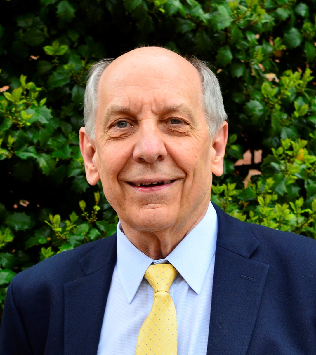 Dr. Louis W. Uccellini smiles at the camera, wearing a navy blazer over a sky blue button-up and a yellow tie